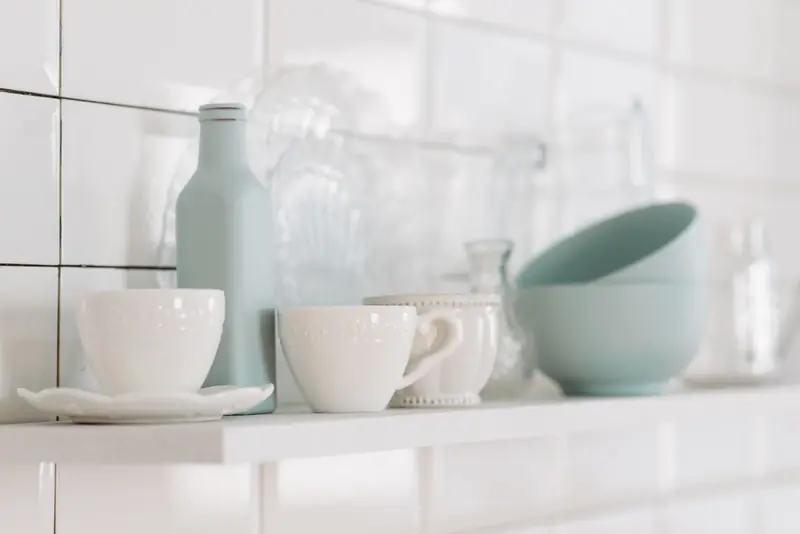 Elegant display of white and pastel kitchen pottery on a shelf in a minimalist style