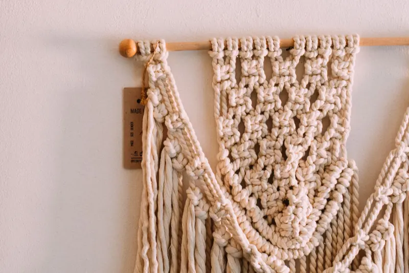 Detailed view of a handmade beige macrame wall hanging showcasing intricate knots and pattern