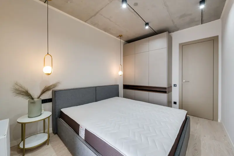 A minimalist bedroom featuring a gray bed, warm lighting, and sleek storage solutions